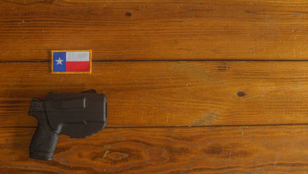semi-automatic handgun, in holster, below a Texas state flag patch on a textured wooden plank background semi-automatic handgun, in holster, below a Texas state flag patch on a textured wooden plank background gun laws stock pictures, royalty-free photos & images