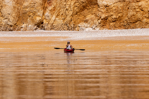 One woman sea kayaker next to golden beach