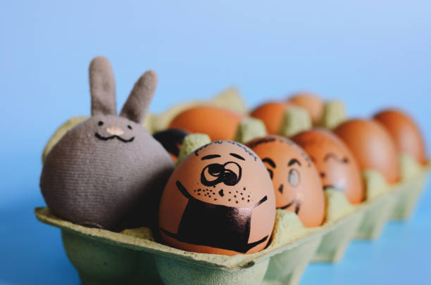 istock Creative Easter eggs with Corona virus (COVID19) protection concepts. Chicken eggs with pills on mini shopping cart with doodle faces wearing medical masks on blue background. Flat lay, DIY. 1324180037