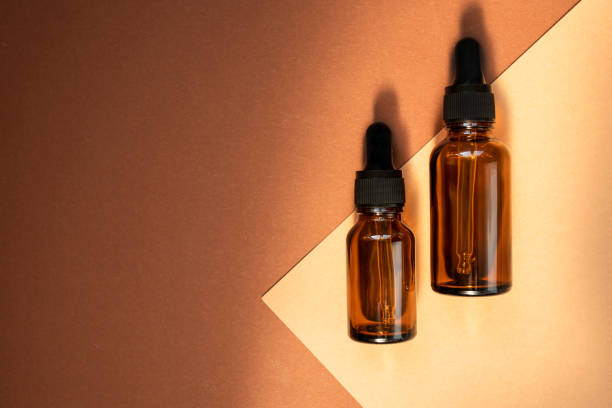 istock Glass dropper bottles on a beige background cast shadows. Top view, place for text. 1324180229