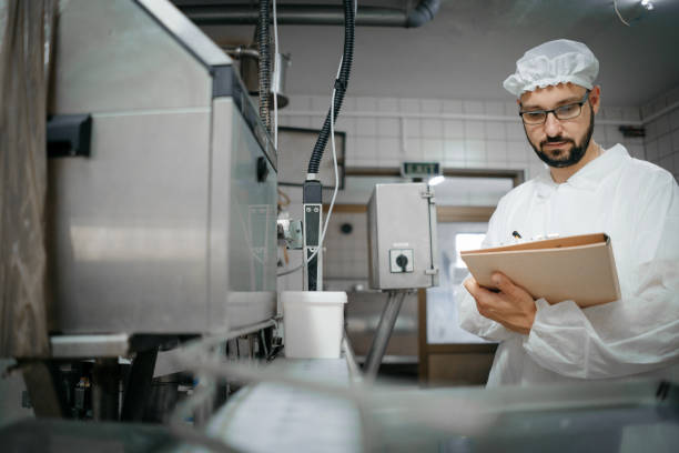 experto tecnólogo tomando parámetros de una máquina industrial en una fábrica de leche - food hygiene fotografías e imágenes de stock