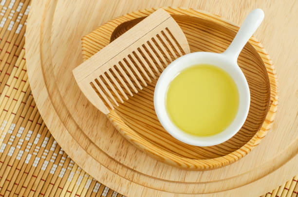 Small white bowl with cosmetic (massage, cleansing) oil and wooden hairbrush. Natural haircare, spa and beauty treatment recipe. Top view, copy space. Small white bowl with cosmetic (massage, cleansing) oil and wooden hairbrush. Natural haircare, spa and beauty treatment recipe. Top view, copy space. castor oil stock pictures, royalty-free photos & images