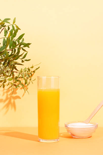 オレンジジュースグラスとコラーゲンパウダー(植物付きテーブル) - scincare ストックフォトと画像