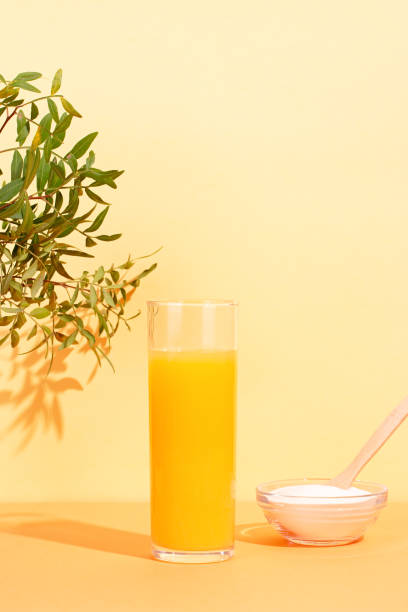 vidro de suco de laranja e pó de colágeno na mesa com planta - scincare - fotografias e filmes do acervo