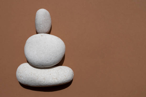 istock Three white smooth stones on top of each other on a beige background. Top view, place for text. 1324185986