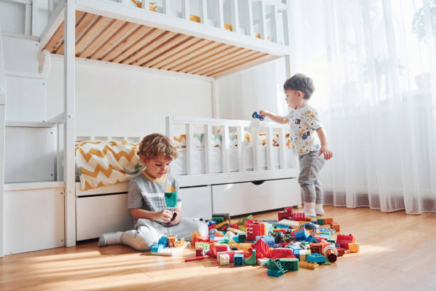 istock Two little boys have fun indoors in the bedroom with plastic construction set 1324186633