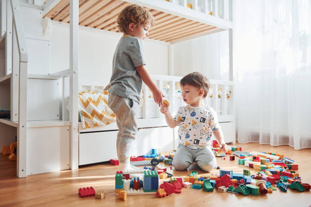 istock Two little boys have fun indoors in the bedroom with plastic construction set 1324186740