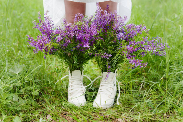 Hipster woman in the park. Creative purple bouquet in boots