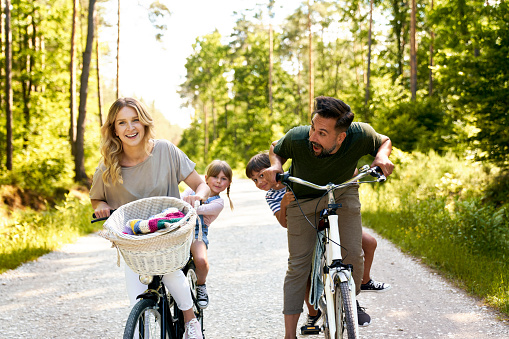 Playful family having fun on a bicycles in the woods