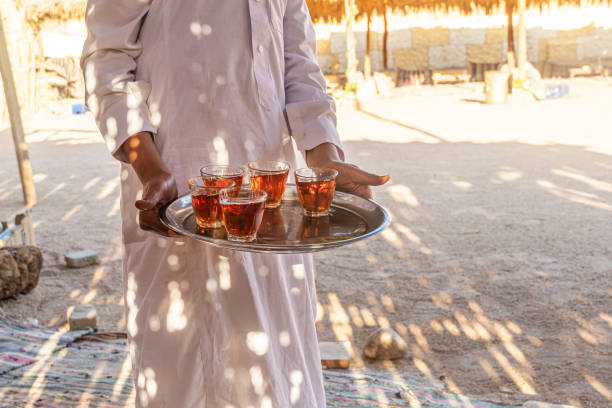 Bedouin welcome a cup of tea with almonds, Sinai. A tray with mugs of traditional Egyptian tea in the waiter's hand. A tray with mugs of traditional Egyptian tea in the waiter's hand. Bedouin welcome a cup of tea with almonds, Sinai. bedouin photos stock pictures, royalty-free photos & images