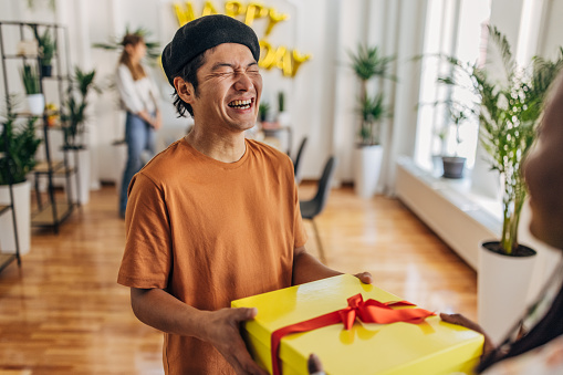 Multi-ethnic group of people, friends bringing presents to a birthday party for their male friend.
