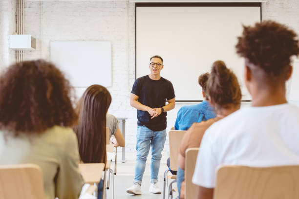 istock Smiling male student giving speech in classroom 1324195193