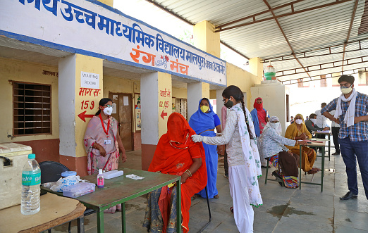 Beawar, Rajasthan, India, May 27, 2021: A medic administers a dose of COVID-19 vaccine to a rural woman in veil at a vaccination centre in Malpura village near Beawar. India's prolonged and devastating wave of Covid-19 infections has gripped cities and overwhelmed urban health resources, but it has also reached deep into rural India, where the true extent of devastation is unknown because of the lack of widespread testing or reliable data.