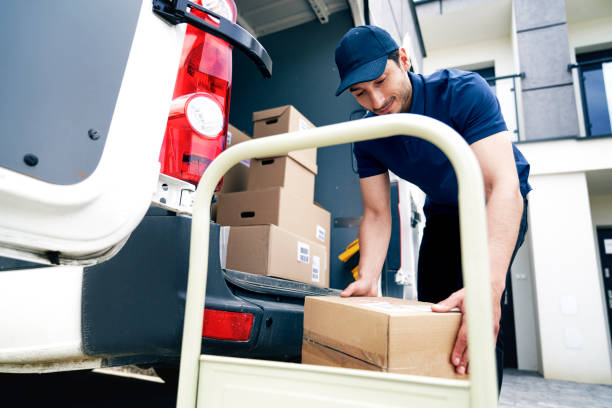 istock Smiling courier unloading packages on the hand truck 1324196511