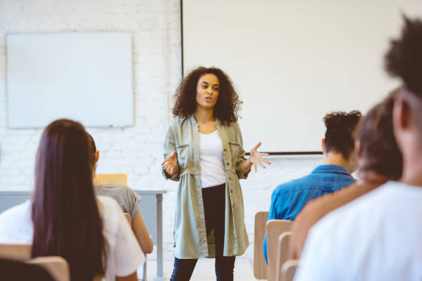 young woman giving speech in classroom - lecture hall university talking student imagens e fotografias de stock