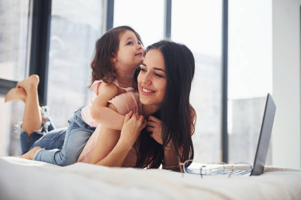 istock Young mother with her daughter spending weekend together in room and using laptop 1324197761