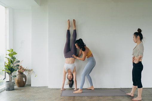 Three Asian women practicing for the perfect handstand