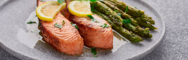 istock Cooked salmon fillet with asparagus in a plate panoramic banner 1324205902