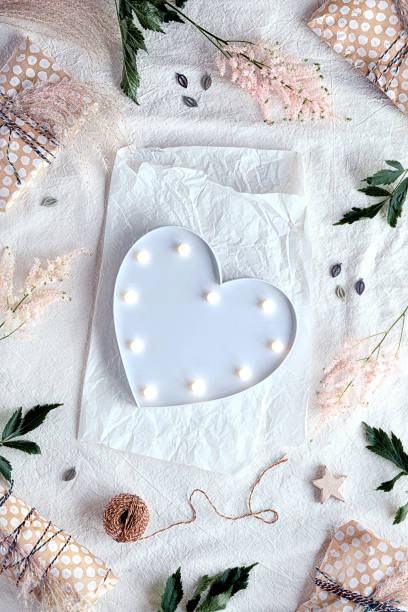 istock Heart lightbox. Background with wild flowers and natural materials. Flat lay on off white textile with white wrapping paper, gift boxes wrapped in recycled craft paper. Pale pink wild flower 1324207074