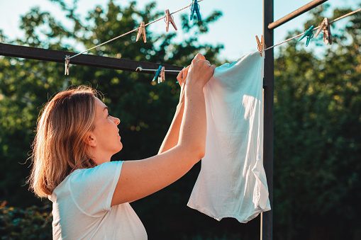 Una joven ama de casa sonriente caucásica colgando la ropa. vertical. Concepto de tareas domésticas photo