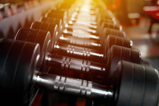 Rack with many different sizes of dumbbells in the gym. Free weights zone. Sunlight enters the window. Focus blur. Copy space