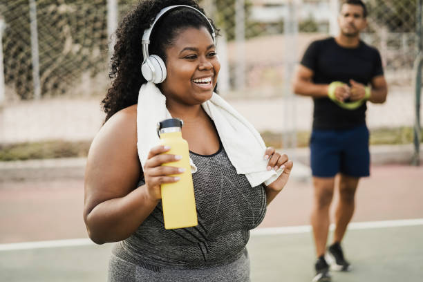 mulher curvilínea fazendo rotina matinal de treino ao ar livre no parque da cidade - foco no rosto - gordo - fotografias e filmes do acervo