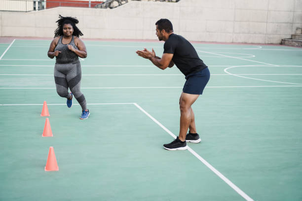 istock Plus size woman and personal trainer doing speed and agility cone drills workout session outdoor - Focus on girl face 1324208857