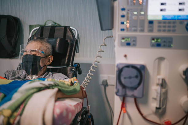 homme âgé chinois asiatique en fauteuil roulant avec écran facial, masque facial sous traitement de dialyse à l’hôpital - dialyse photos et images de collection