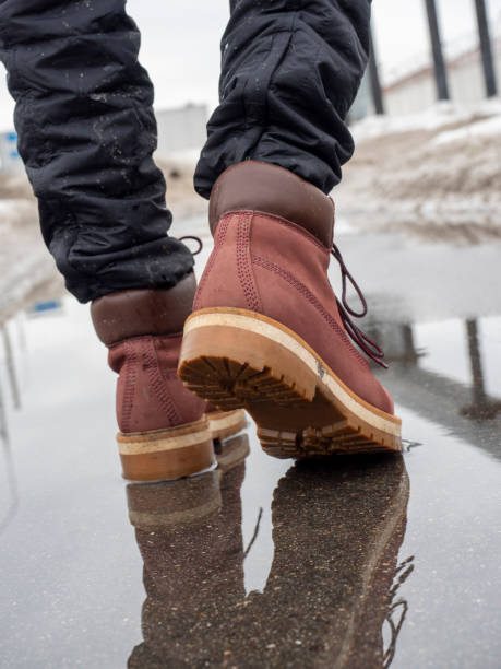 istock a man walks through a puddle in terracotta leather shoes. Close-up, reflection in a puddle, littered horizon. Walking man concept, journey 1324216356