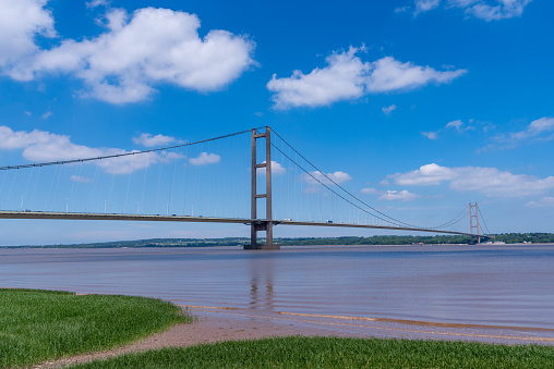 View of the Humber suspension bridge and river with blue sky on a bright sunny day.