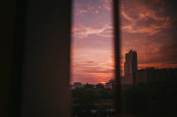 istock Sunset looking through window at city with reflection on window with sunset 1324220296