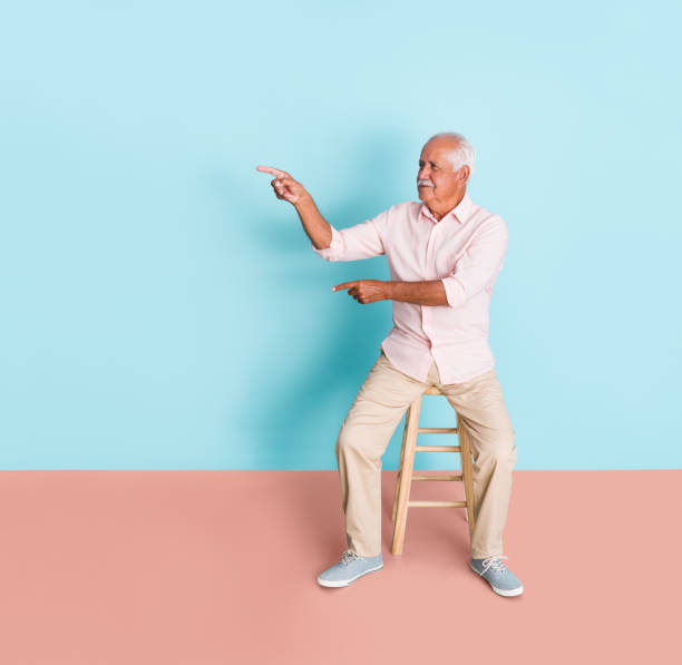 istock Senior man sitting and pointing to side 1324220771