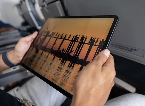 Close-up on a traveler watching a movie in an airplane using his tablet - onboard entertainment concepts **PHOTO BELONGS TO US**