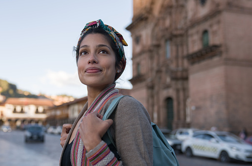 Portrait of a happy woman sightseeing walking around Cusco by the Cathedral and smiling - travel destinations concepts
