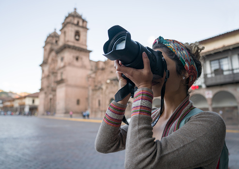 Photographer sightseeing in Cusco and taking pictures with her professional camera - travel concepts