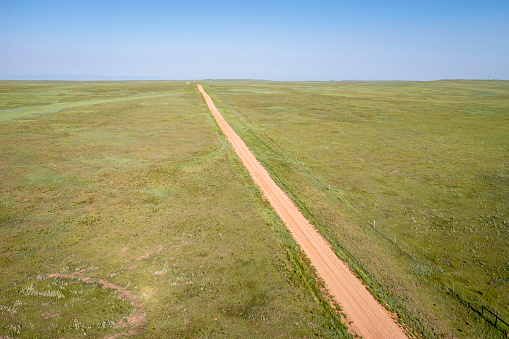 dirt remote road going through green prairie, Pawnee National Grassland in Colorado, aerial view
