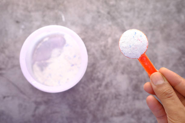 istock Washing powder in plastic spoon on black background top view. 1324230648