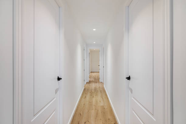 Interior of long narrow hallway with closed doors, wooden floor and white walls in apartment designed in minimal style Interior of long narrow hallway with closed doors, wooden floor and white walls in apartment designed in minimal style. narrow photos stock pictures, royalty-free photos & images