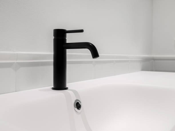 istock Small black faucet and sink in white clean bathroom. Copy space. 1324230671
