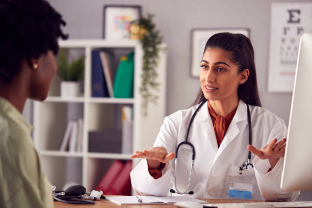 Female Doctor In White Coat Having Meeting With Woman Patient In Office Female Doctor In White Coat Having Meeting With Woman Patient In Office womens issues stock pictures, royalty-free photos & images