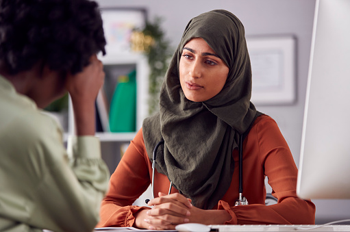 Female Doctor Or Consultant Wearing Headscarf Having Meeting With Unhappy Female Patient