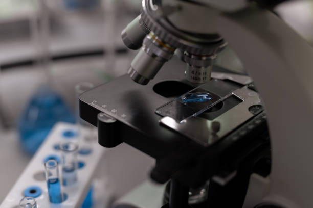 istock Part of microscope and flasks with blue liquid substance 1324230934