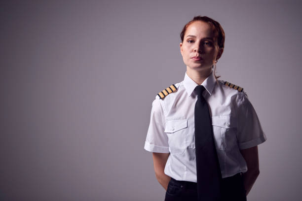 istock Studio Portrait Of Serious Young Female Airline Pilot Against Plain Background 1324230955