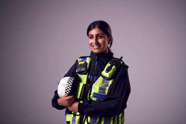 Studio Portrait Of Smiling Young Female Police Officer Against Plain Background Studio Portrait Of Smiling Young Female Police Officer Against Plain Background police force stock pictures, royalty-free photos & images