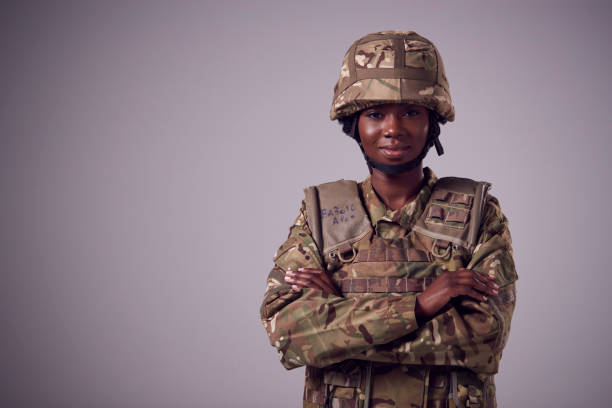 Studio Portrait Of Smiling Young Female Soldier In Military Uniform Against Plain Background Studio Portrait Of Smiling Young Female Soldier In Military Uniform Against Plain Background military uniform stock pictures, royalty-free photos & images
