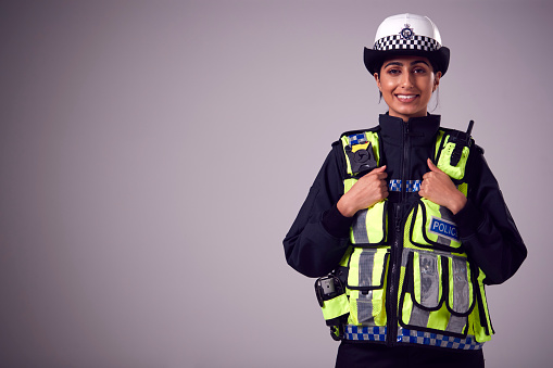 A male prison guard warden or policeman in uniform with duty belt and radio unit.   Standing with arms crossed and looking up.  White background