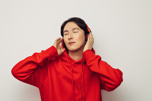 Emotional asian man wearing hoodie and listening to music