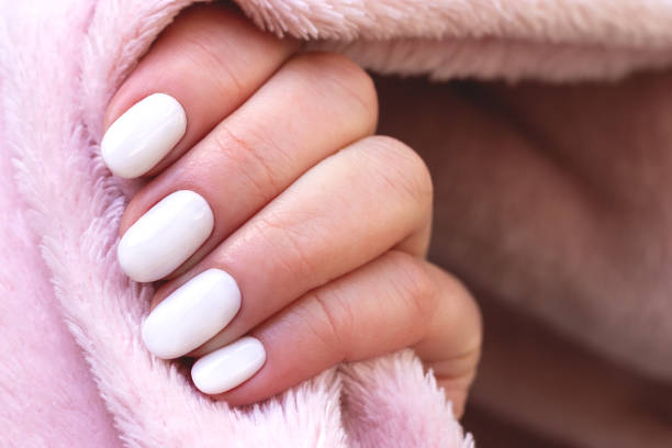 istock Hand with white nails on pink textile background 1324233944