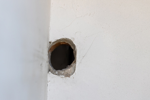 Holes on the cement wall Caused by drilling. hole in in white cement wall as a background. Hole on the wall.