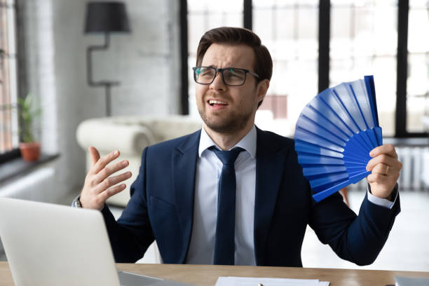 funcionário de escritório masculino exausto sofrendo de calor, ar quente abafada - office fan - fotografias e filmes do acervo